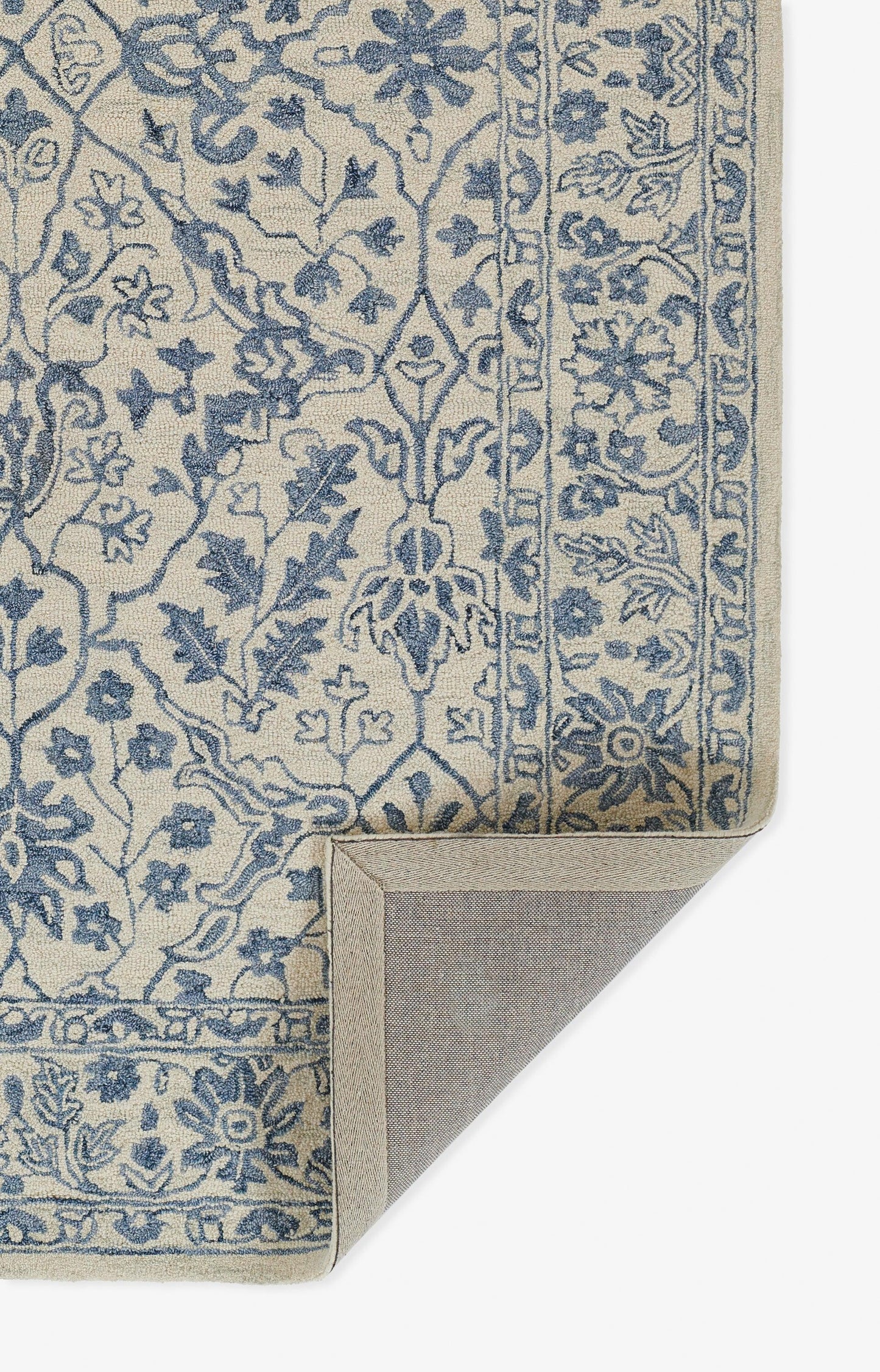 Blue floral on beige rug with ornate border; traditional oriental style, corner folded to show the backing.
