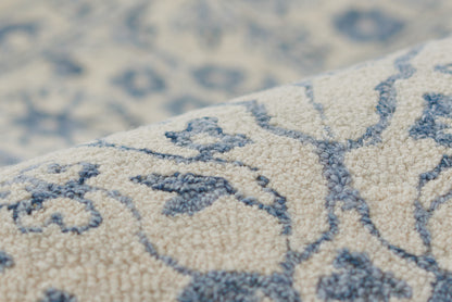 Close-up of ivory-beige rug with blue arabesque floral pattern and plush woven pile.