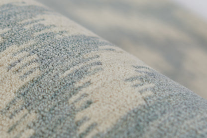Close-up of blue and beige textured rug with looped pile and subtle striped pattern.