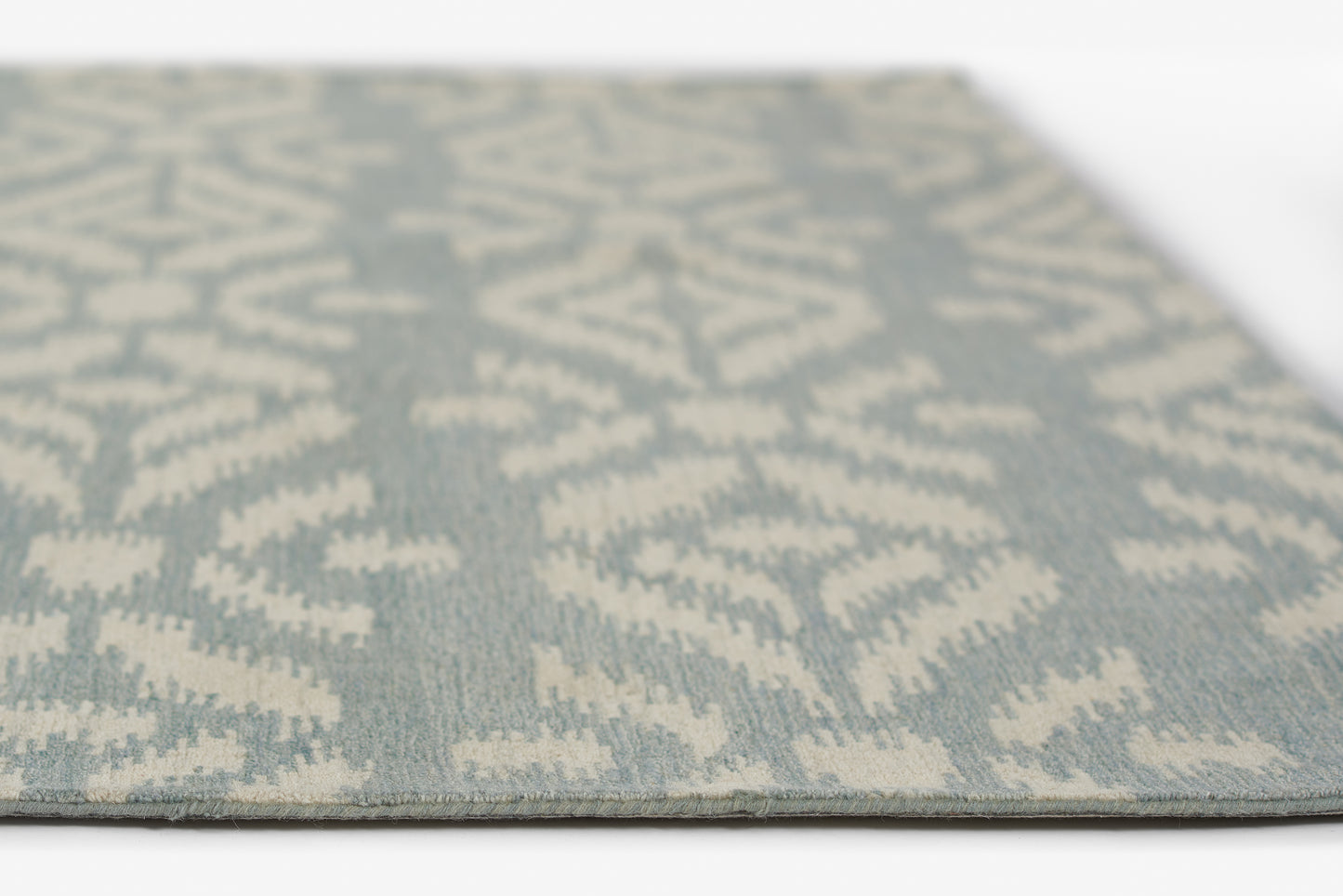 Rectangular flat-weave rug, 8' x 10', pale blue with ivory geometric ikat pattern; modern boho living-room accent.