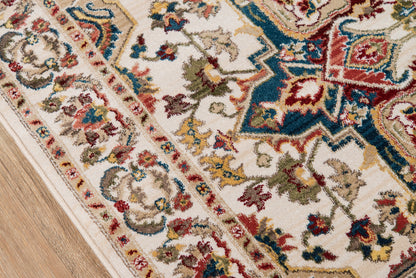Rectangular woven oriental rug with ivory base and multicolor red, blue, green, and gold floral motifs on a light wood floor.