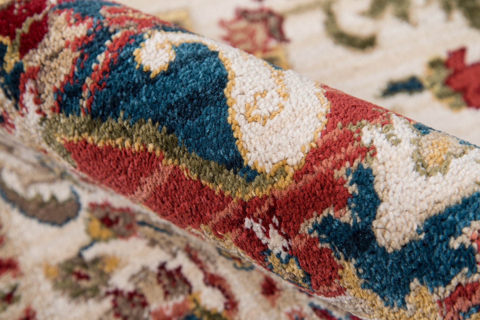 Persian-style wool rug close-up with red, teal blue, cream & gold floral pattern; plush pile.