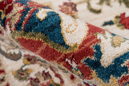 Persian-style wool rug close-up with red, teal blue, cream & gold floral pattern; plush pile.