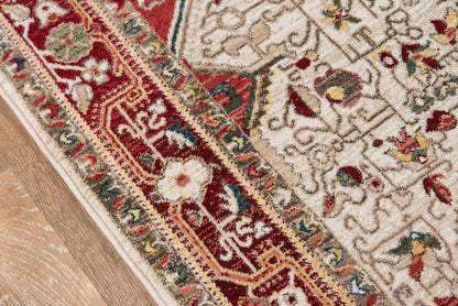 Close-up of oriental rug corner with red border, ivory field and floral motifs on a wooden floor.