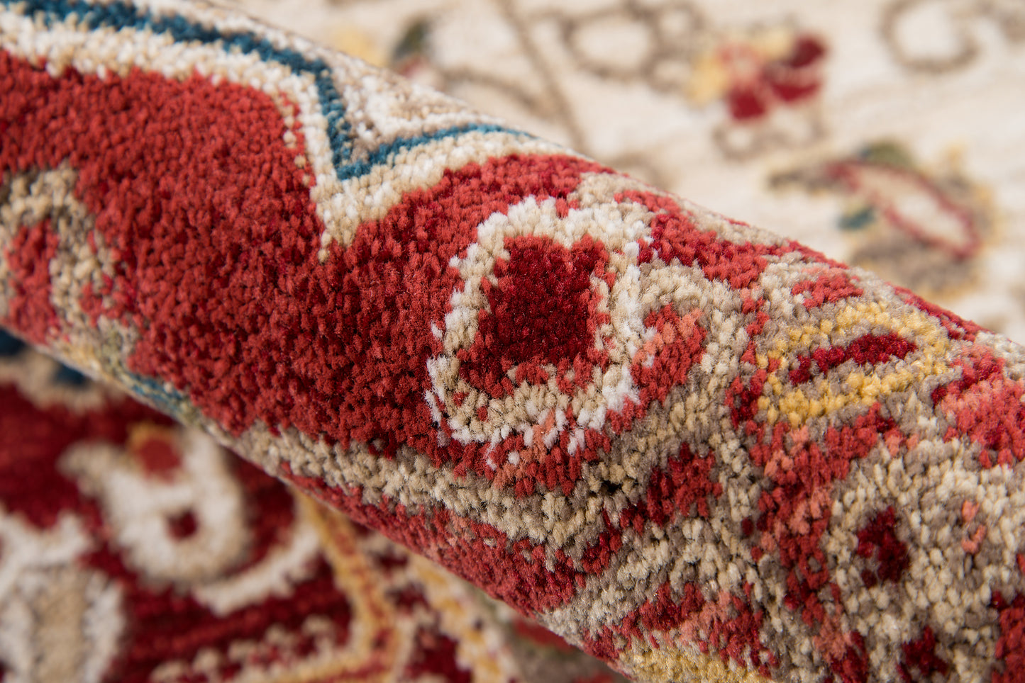 Close-up of red, cream, and blue geometric patterned woven rug with plush pile.