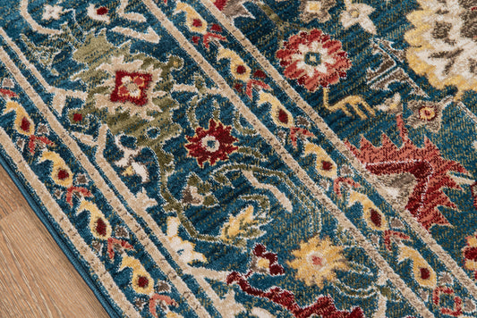 Blue floral oriental area rug with red, cream and gold motifs and decorative border on wood floor.