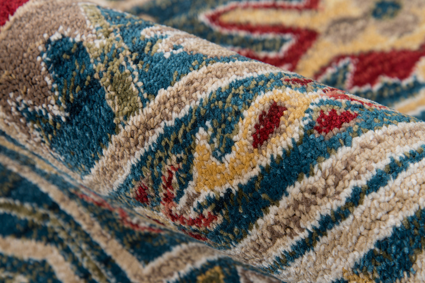 Close-up of a multicolor woven rug with blue, beige, cream, red and yellow geometric pattern and plush pile.