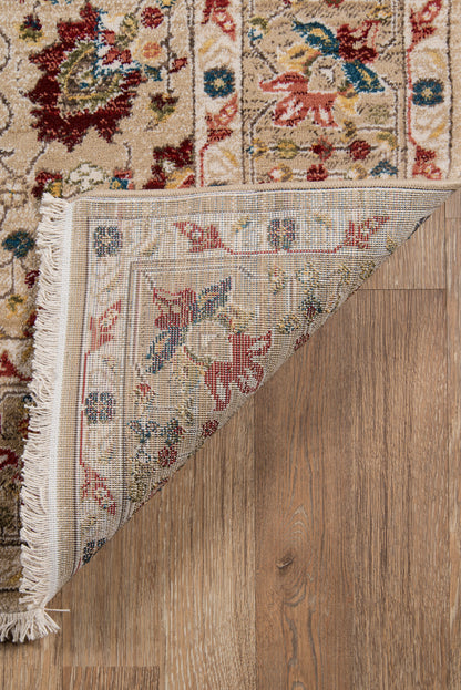 Beige traditional oriental rug with blue, pink and red floral motifs; fringe edge, folded on a wooden floor.