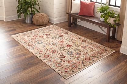 Rectangular cream Oriental area rug with red, blue and gold floral medallions on a dark-wood floor in a living room.