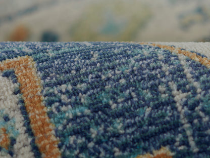 Close-up of a blue woven rug with teal and orange accents and a textured geometric pattern.