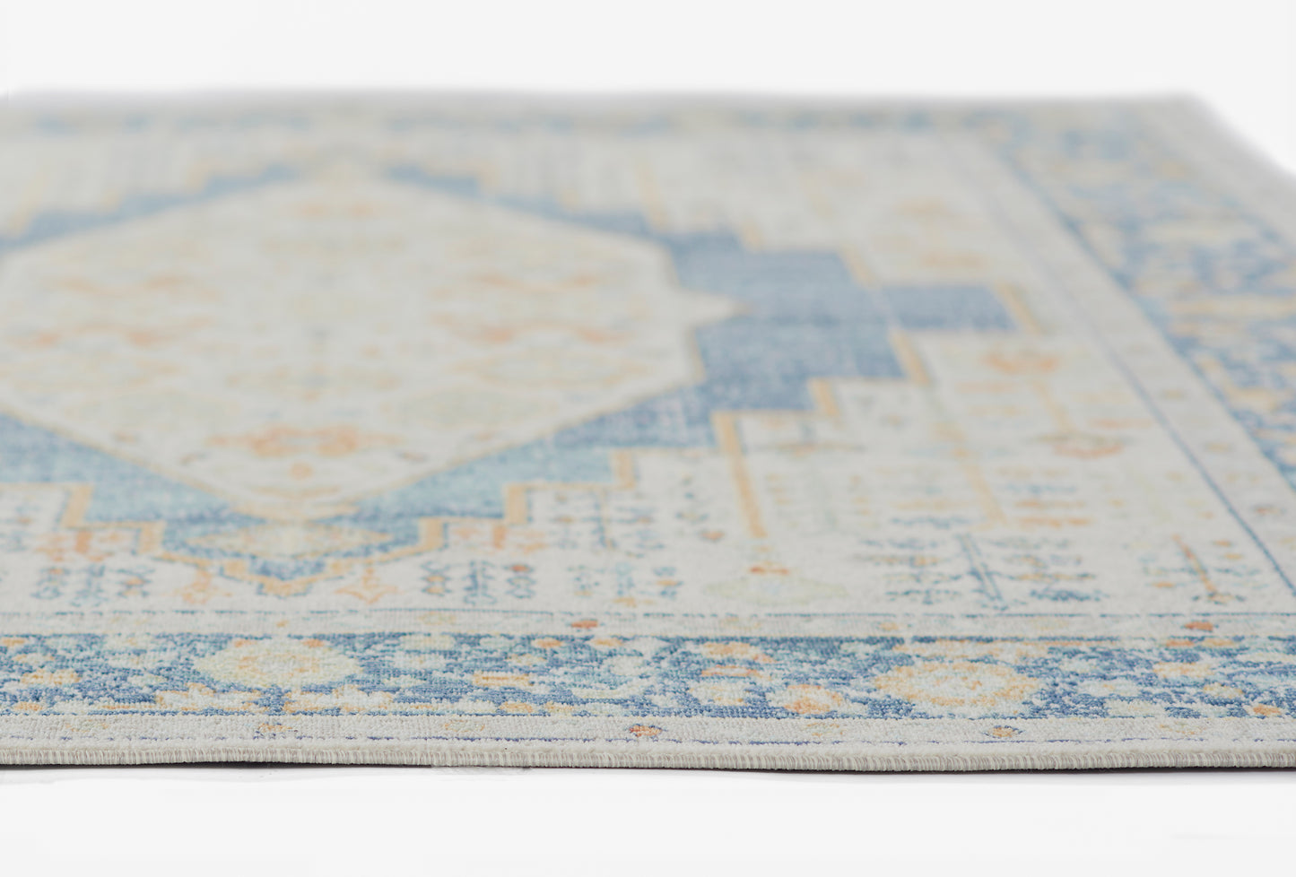 Close-up of a blue & ivory distressed rug with a geometric medallion and subtle orange accents.