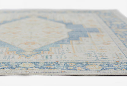 Close-up of a blue & ivory distressed rug with a geometric medallion and subtle orange accents.