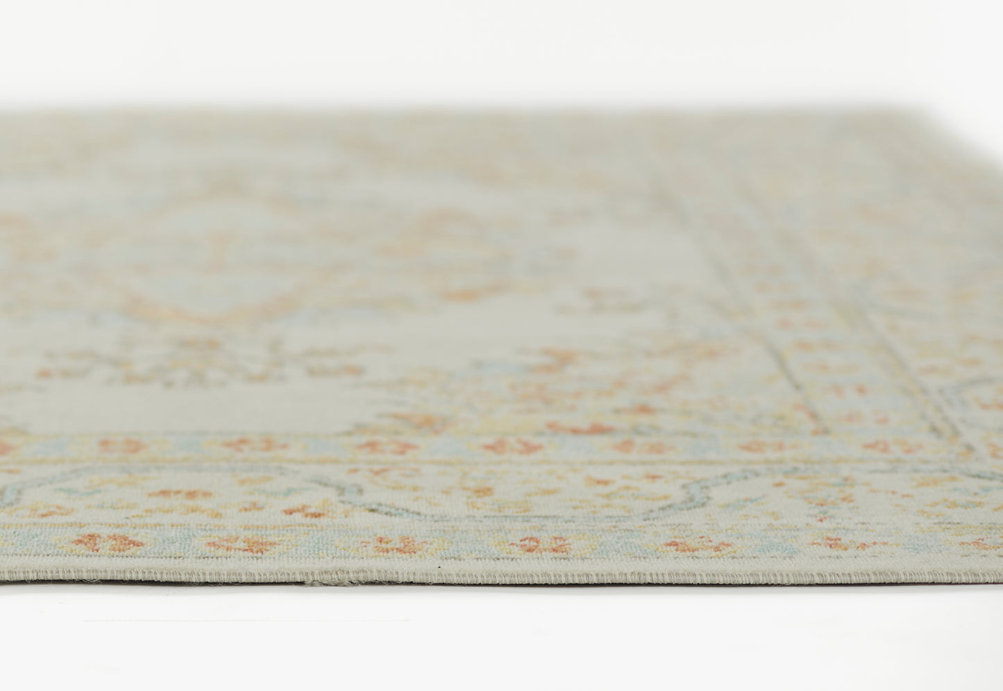 Beige floral area rug (2' x 3') with subtle blue & orange accents, close-up edge view, soft low-pile fabric.