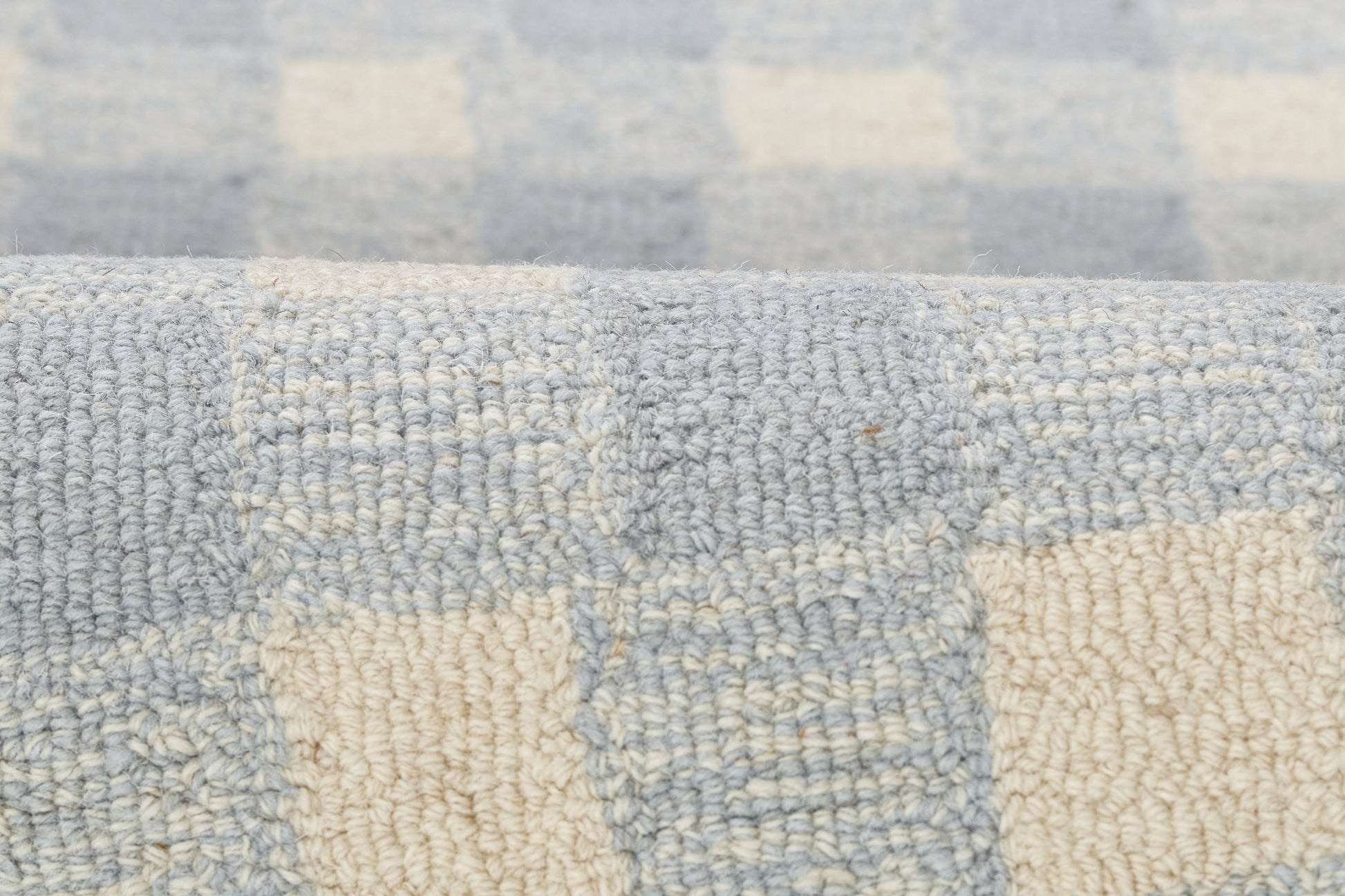 Close-up of pale blue and ivory checkered woven textile with soft boucle texture, suitable as rug or throw.