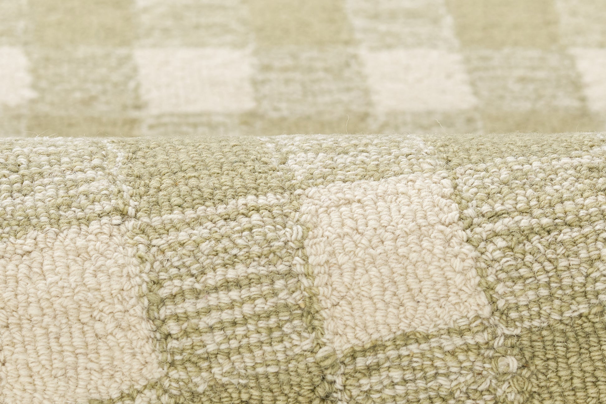 Close-up of cream and sage green checkered woven boucle rug with soft textured fibers.