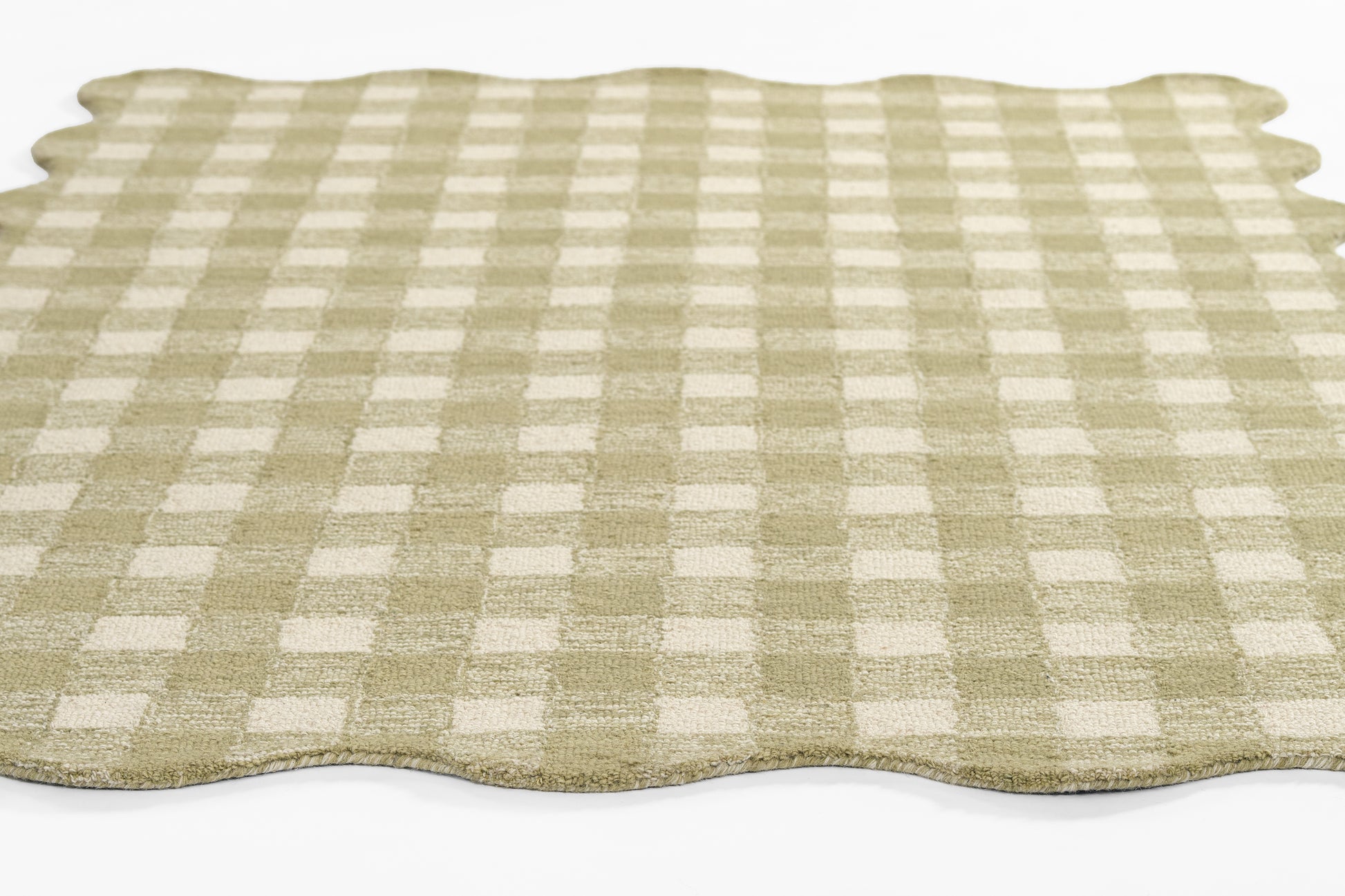 Beige and white gingham area rug with scalloped edges.