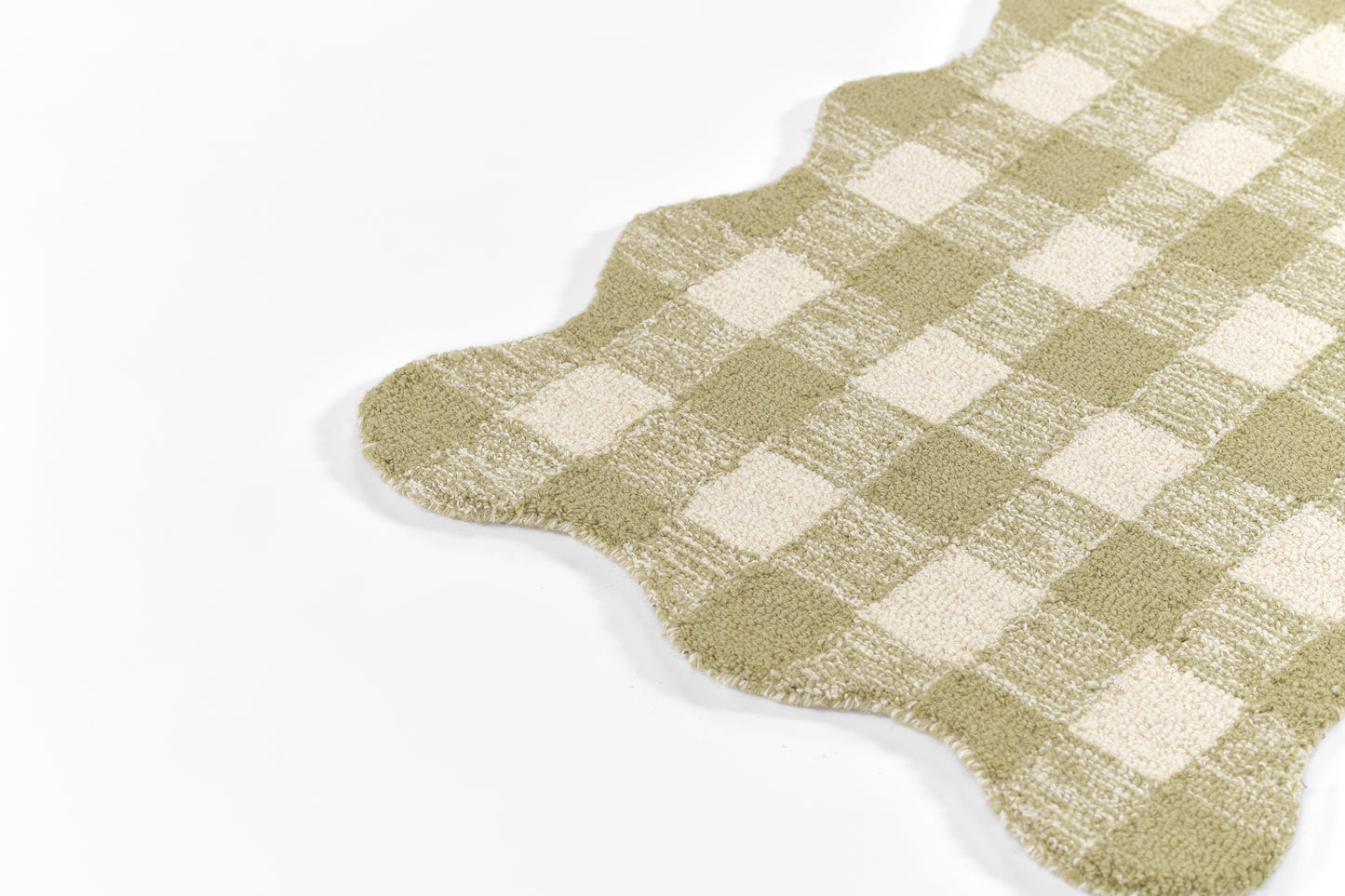 Scalloped-edge area rug in olive green and cream gingham pattern with soft pile.