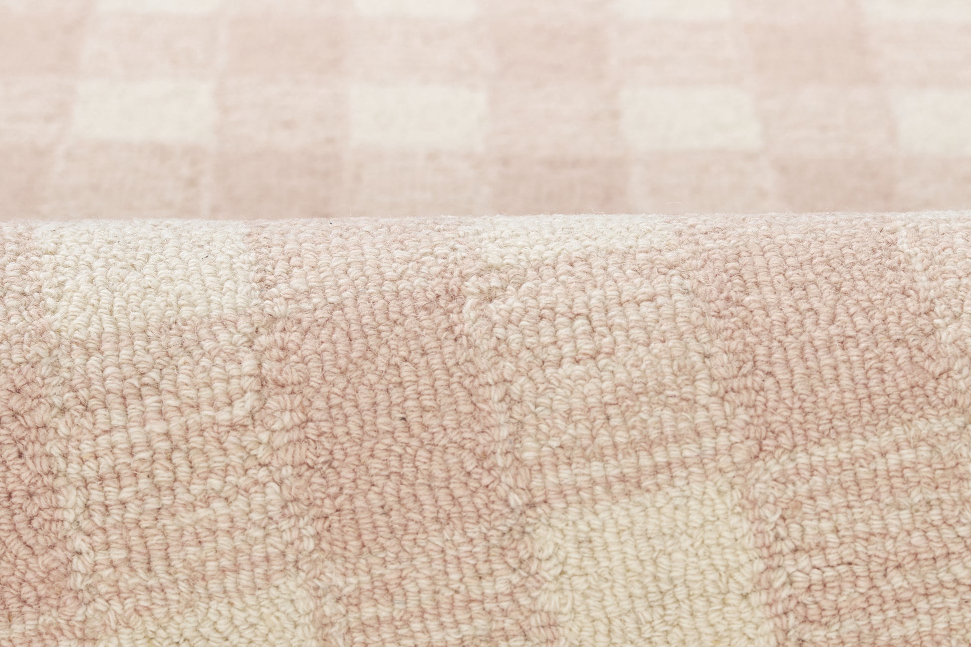 Soft pink and cream checkered rug with plush texture and rolled edge, 2' x 3'.