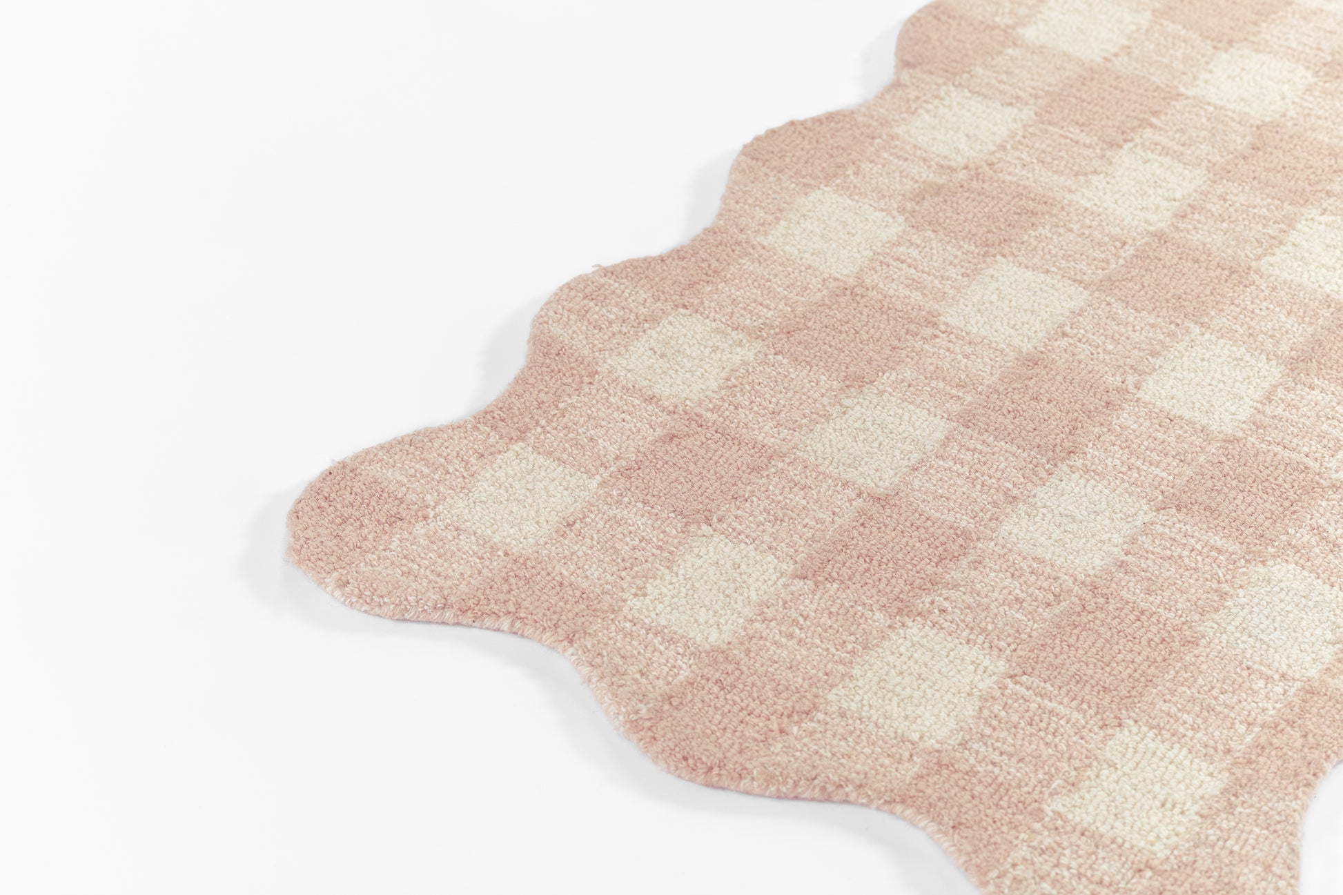 Pink and cream checkered scalloped rug with soft terry texture; cozy home decor mat.