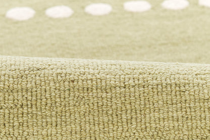 Beige olive looped rug texture with dense woven pile and faint white polka dots along the edge.