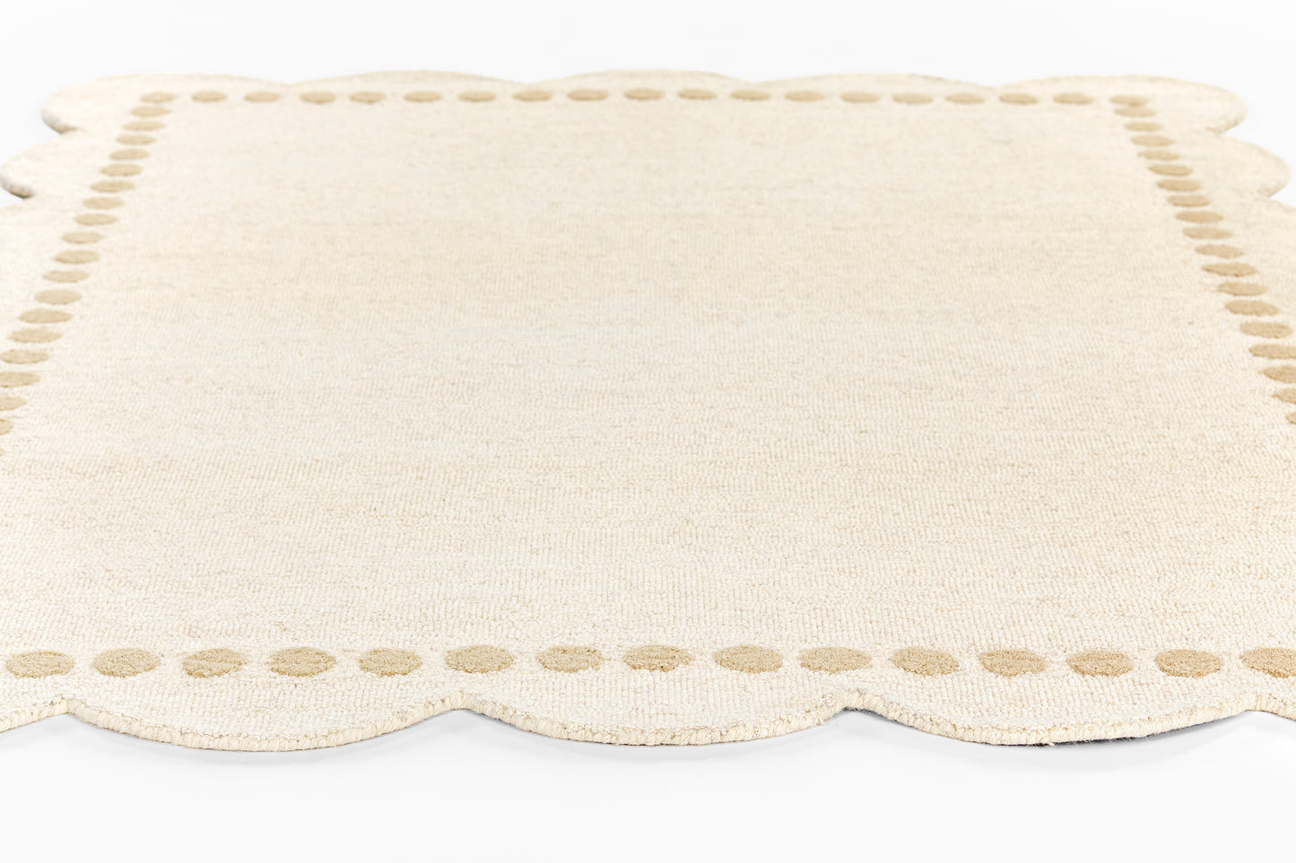 Cream woven rug runner with scalloped edges and a dotted border, 2' x 8'.