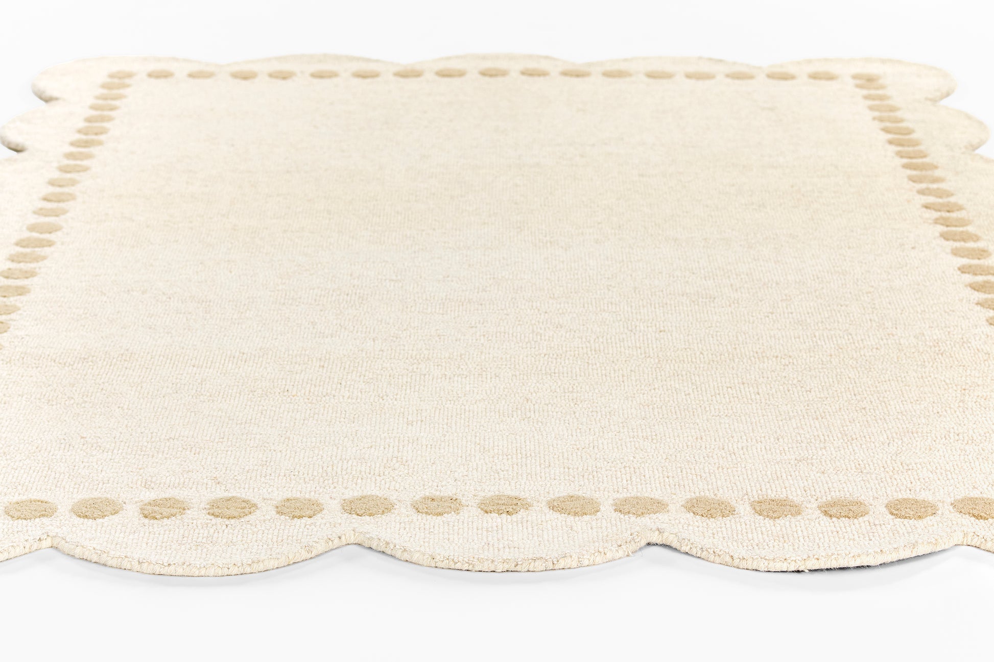 Cream woven rug runner with scalloped edges and a dotted border, 2' x 8'.