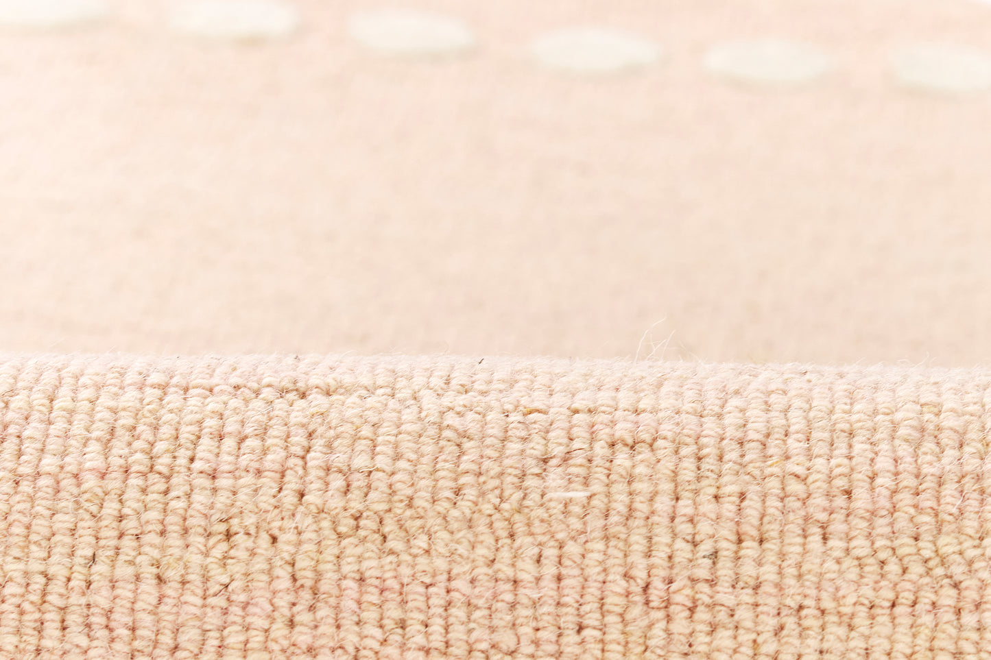 Close-up of peach-pink woven rug with looped pile and subtle dotted pattern.