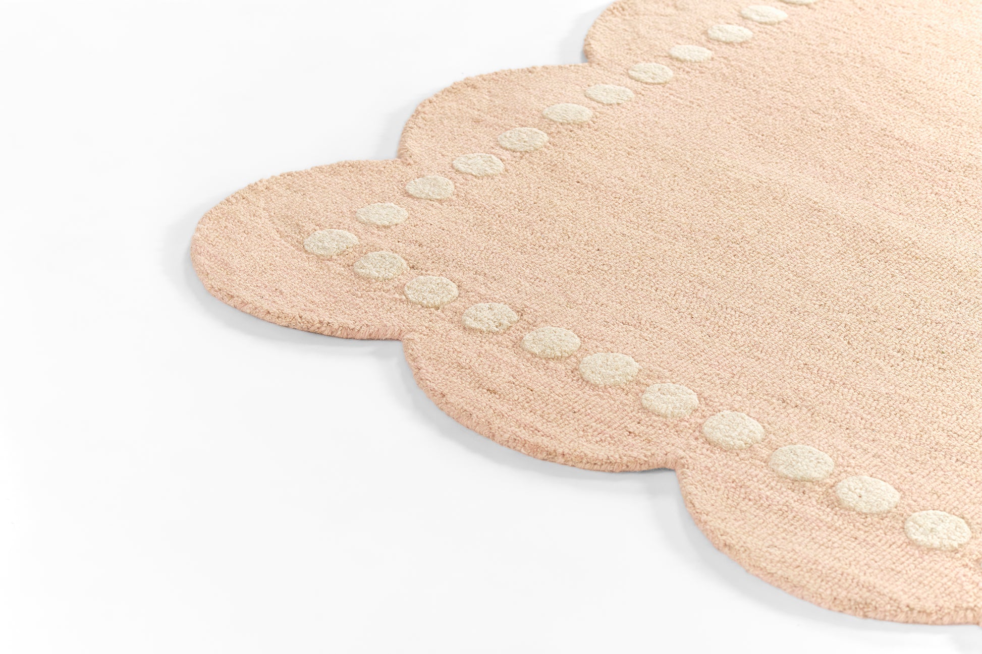 Beige plush cloud-shaped rug with white stitched dot border along a scalloped edge.