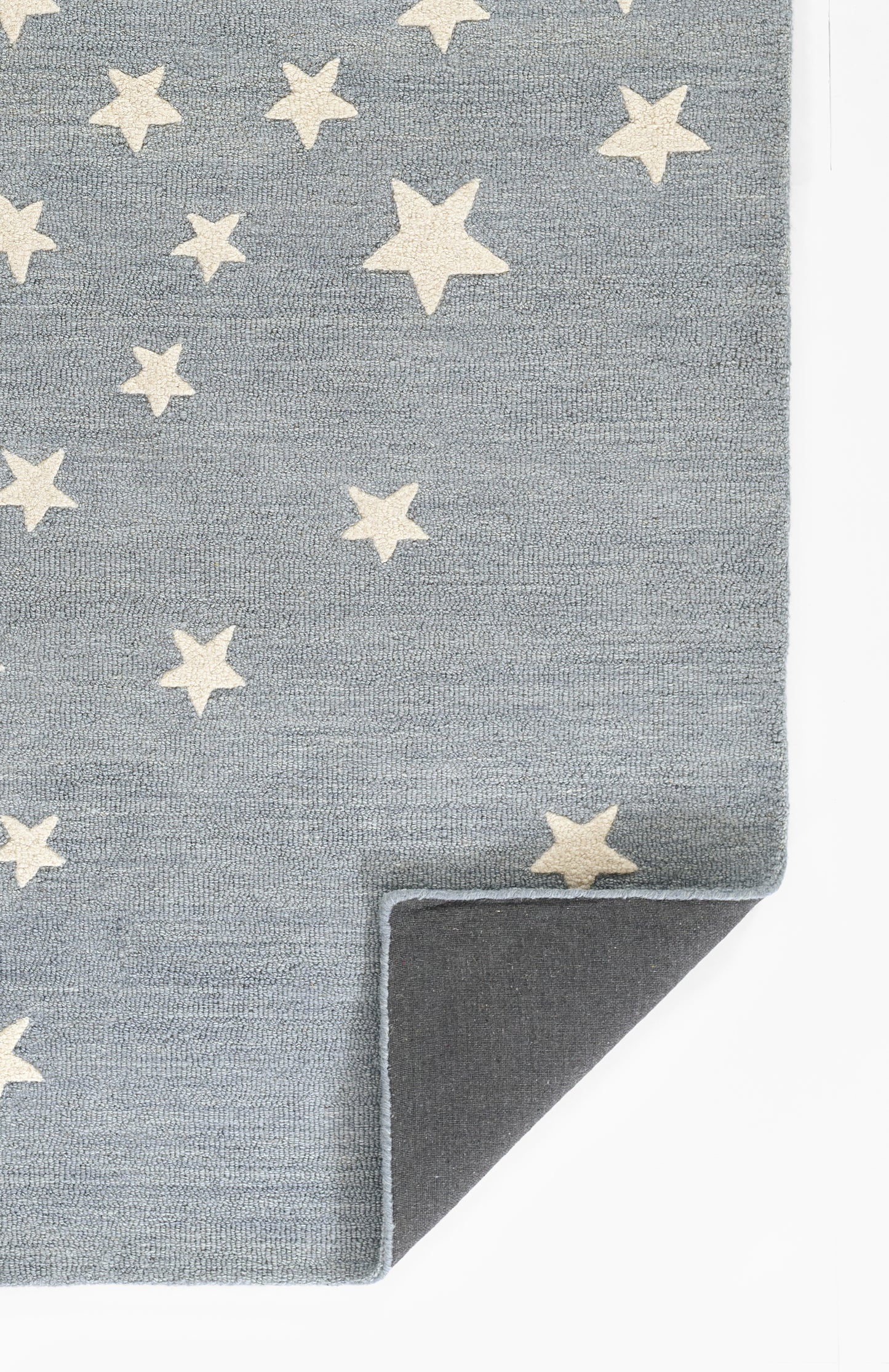 Blue-grey rug with cream-white star pattern, folded corner showing dark underside.