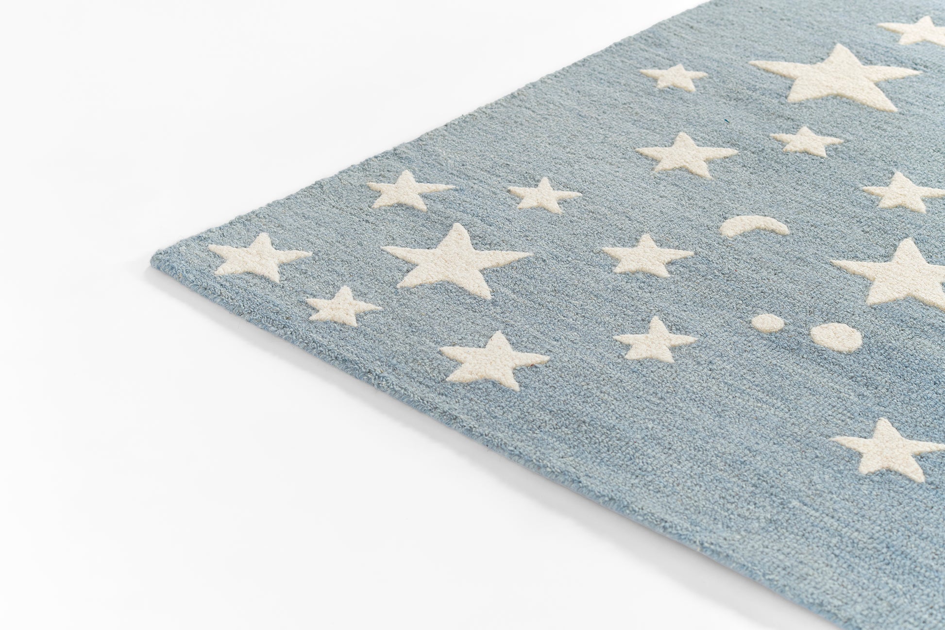 Blue 5' round rug with white star and moon shapes, soft textured pile, diagonal corner view for cozy decor.