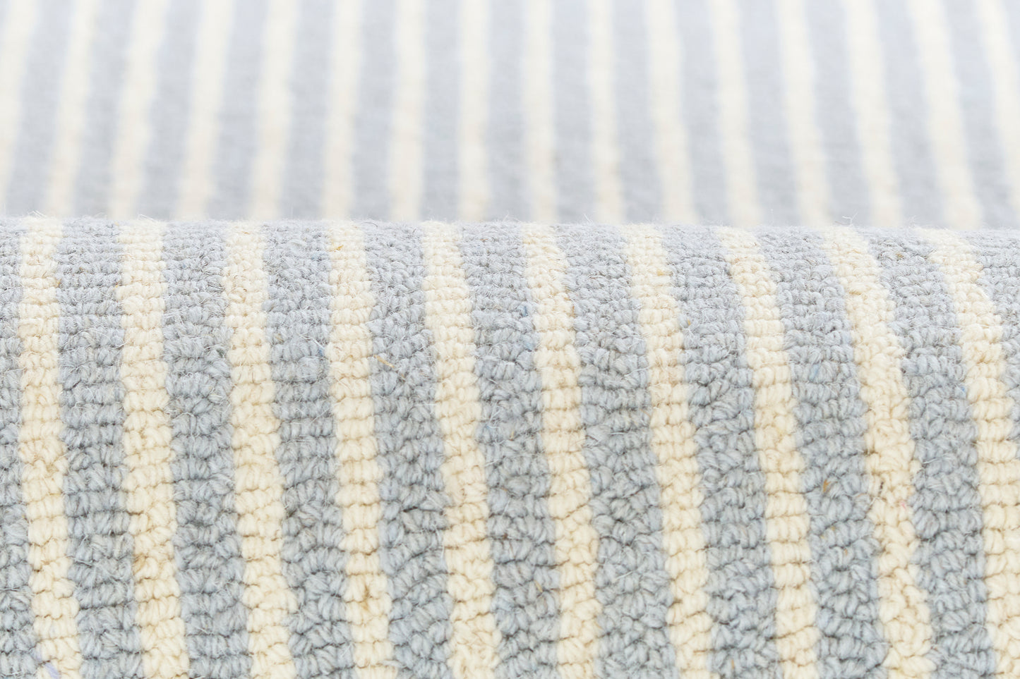 Close-up of light blue and ivory striped rug with plush loop texture.