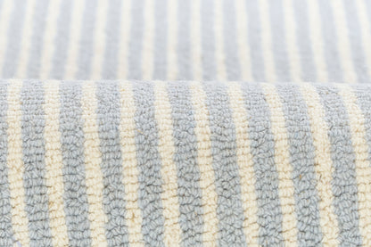 Close-up of light blue and ivory striped rug with plush loop texture.