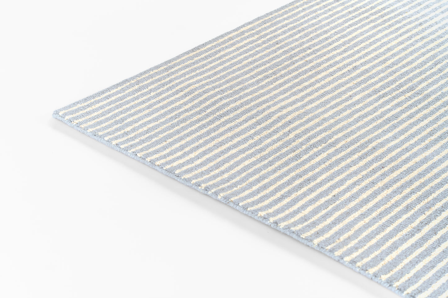 Blue and white striped runner rug, rectangular woven, corner view, soft textured fabric.