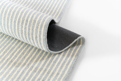 Blue and white striped rug, folded, showing soft texture and dark underside.