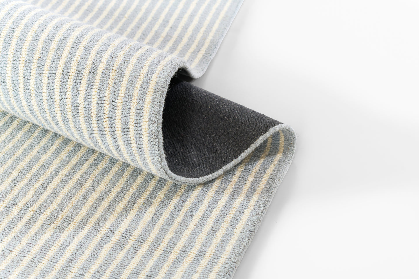 Blue and white striped towel with soft terry texture, folded edge curling over, dark underside visible.