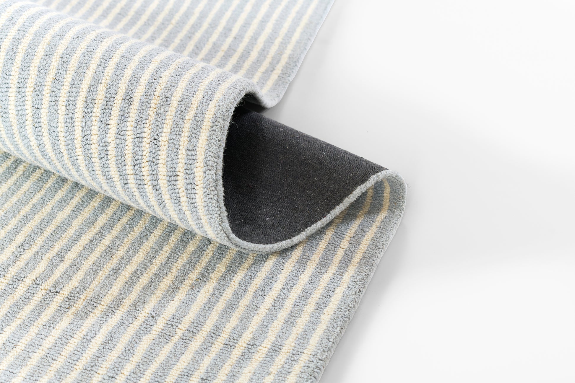 Blue and white striped towel with soft terry texture, folded edge curling over, dark underside visible.