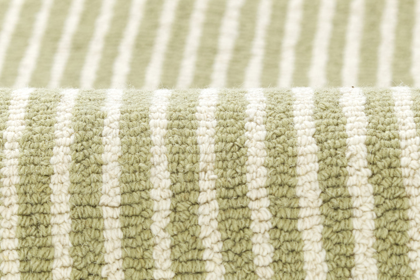Close-up of olive green and white striped rug with plush loop-pile texture and rolled edge.