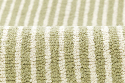Close-up of olive green and white striped rug with plush loop-pile texture and rolled edge.