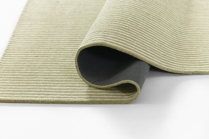 Beige-green ribbed rug sample, partially rolled with dark underside showing.