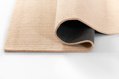 Beige textured woven rug with rolled edge, showing black non-slip underside.