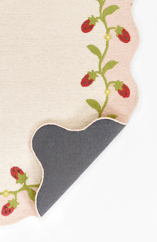 Beige rug with a red floral vine and green leaves along the edge; navy curved patch and scalloped border.