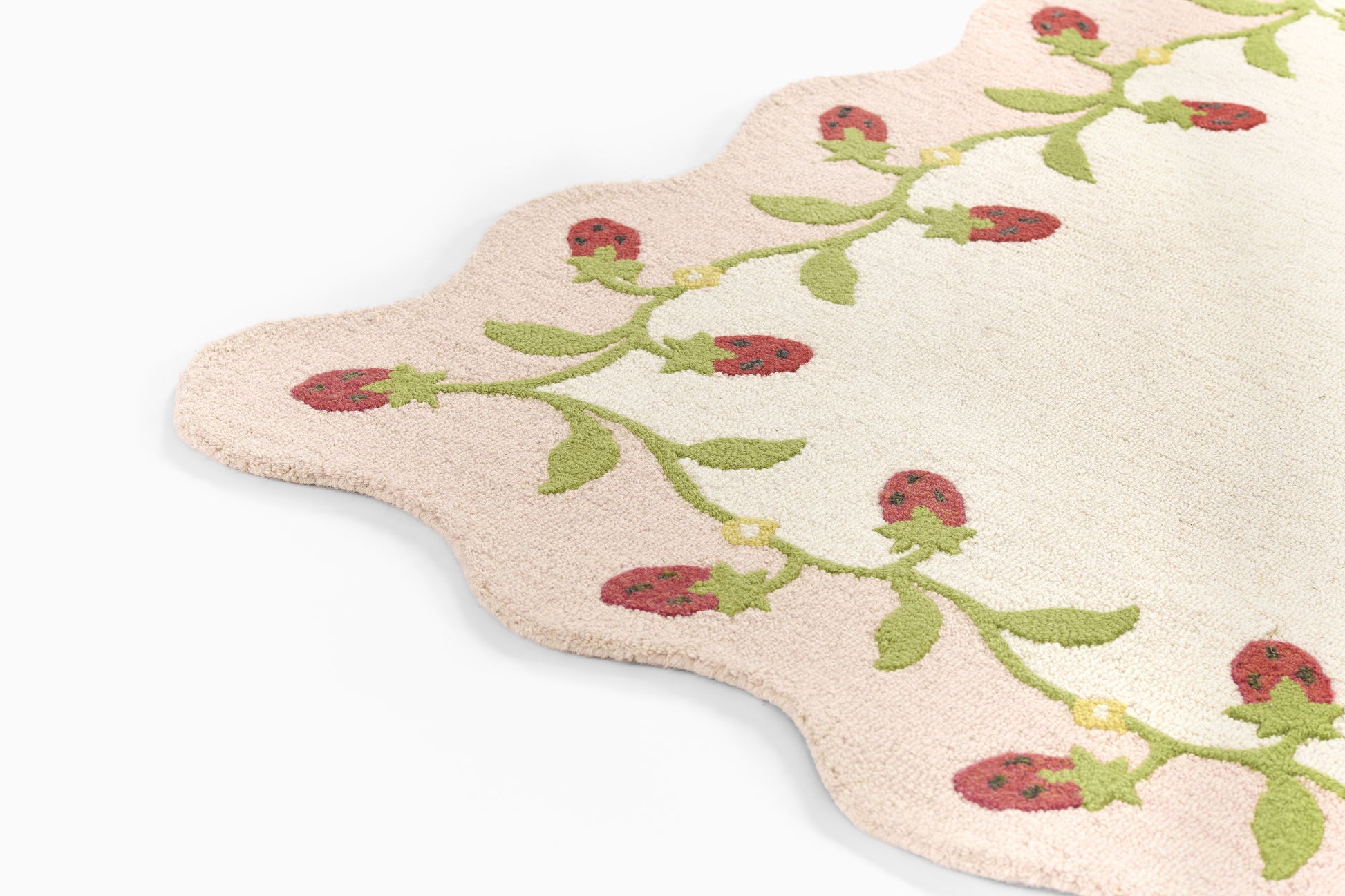 Soft pink scalloped bath mat with green vine and red ladybug embroidery; cotton terry rug for bathroom.