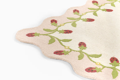 Soft pink scalloped bath mat with green vine and red ladybug embroidery; cotton terry rug for bathroom.