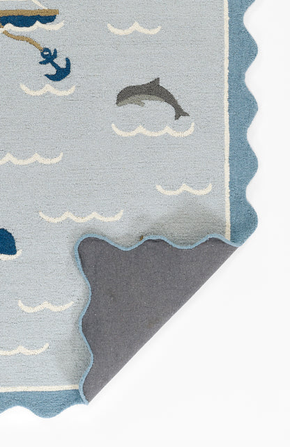 Ocean-themed light blue rug with white wave patterns, dolphin and anchor accents; scalloped edge and soft backing.