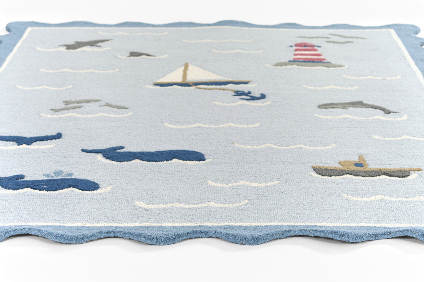 Coastal nautical runner rug in light blue with sailboats, lighthouse and waves; scalloped blue edge.