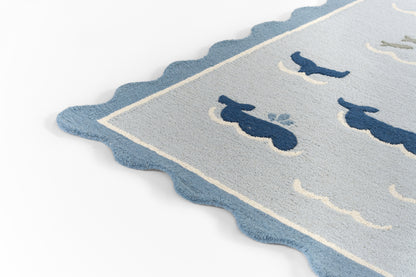 Soft rug with scalloped blue edge and pale gray-blue field featuring navy bird silhouettes.