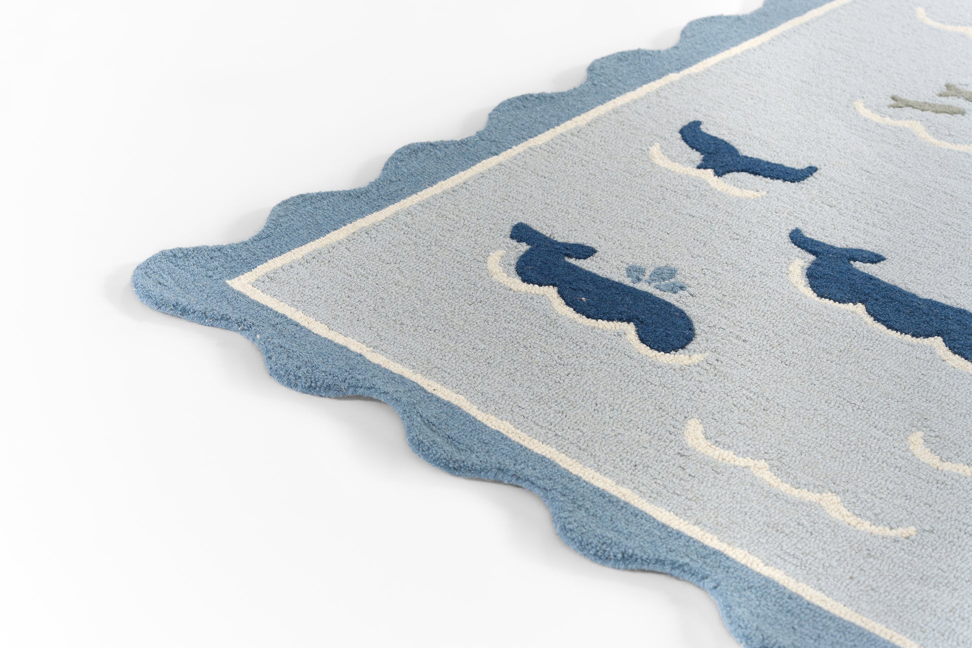 Scalloped-edge blue rug with light gray field and navy whale silhouettes, coastal decorative style.