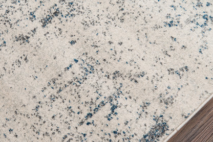 Ivory speckled area rug with blue-gray flecks, close-up edge against wood floor