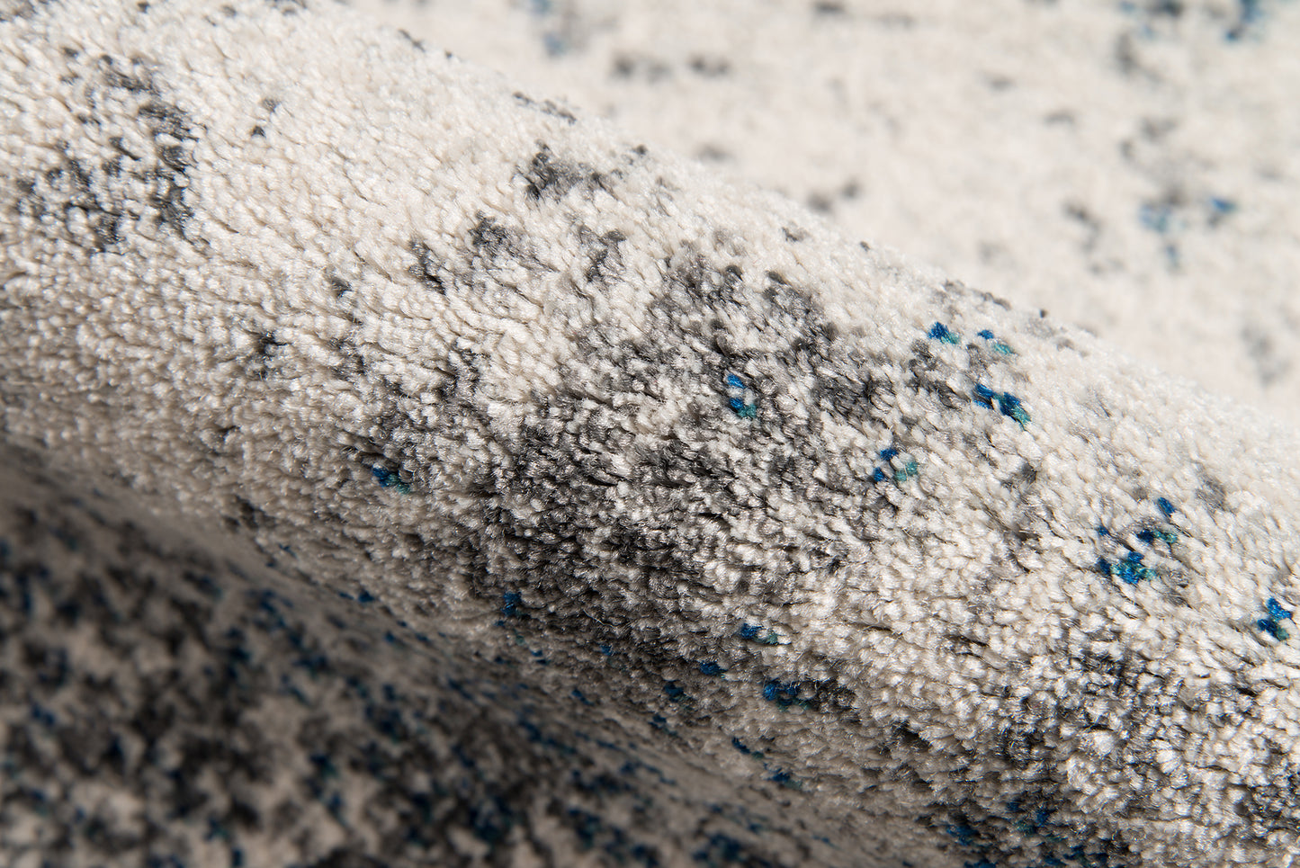 Ivory tufted area rug with gray speckles and blue flecks; loft-style 5' x 8' area rug.