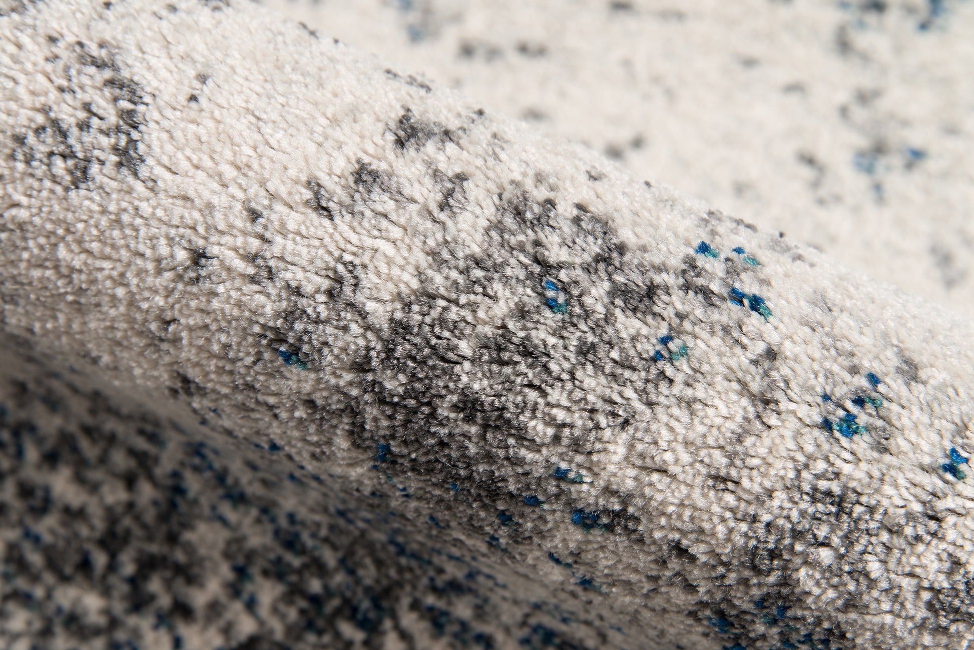 Ivory tufted area rug with gray speckles and blue flecks; loft-style 5' x 8' area rug.